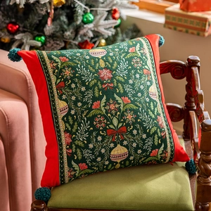 Dettaglio copricuscino jacquard con fiori natalizi rossi e nappine verdi