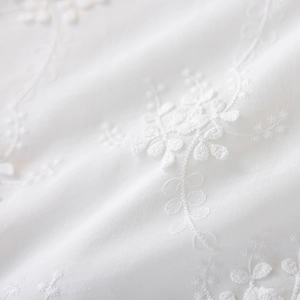Macro detail of high-quality white cotton pillowcase with delicate floral embroidery