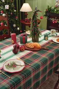 Close-up of Christmas table runner with embroidered red trees on a plaid tablecloth