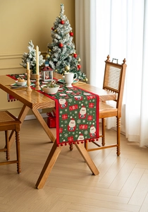 Detail of Christmas table runner with forest green jacquard, Santa pattern and red pom-poms