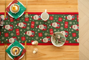 Detail of Christmas table runner with Santa Claus, gift boxes, and snowflakes on wood table
