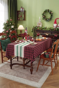 Close-up of red plaid tablecloth and beige table runner with green Christmas tree pattern