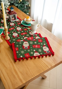 Detail of Christmas table runner with Santa pattern, red pom-poms and festive decor