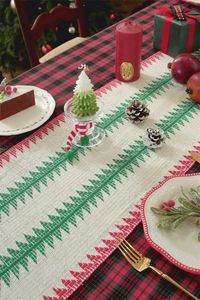 Close-up of Christmas table runner with green pine trees and red scalloped borders