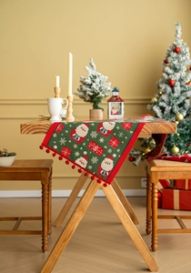 Macro view of Christmas table runner with knitted Santa Claus and red pom-pom edge