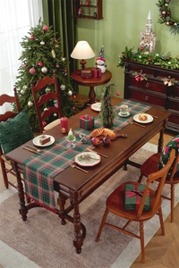 Detail of red and green plaid table runner with red pompoms and Christmas tree pillow