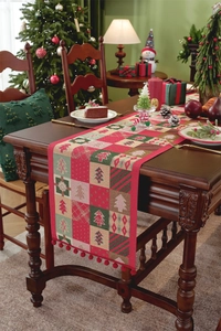 Detailed view of Christmas table runner with festive trees and red pom-poms on wood