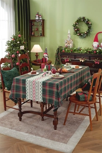Close-up of red and green plaid tablecloth with festive table runner and Christmas cushions