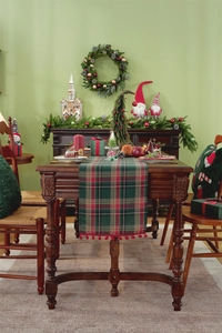 Close-up of Christmas table runner with red and green plaid pattern and red pom-poms