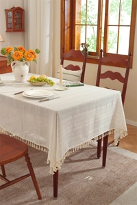 Close-up of cream linen-texture tablecloth with stripe patterns and decorative tassels