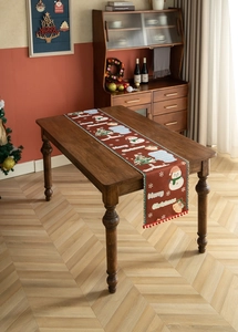 Close-up of a festive red Christmas table runner with snowman patterns and red pompom trim