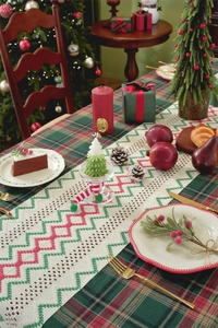Close-up of crochet Christmas table runner with red and green wave patterns on beige fabric
