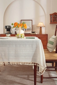 Detailed texture of off-white linen tablecloth with stripes and delicate fringe edges