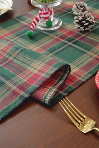 Detailed close-up of red and green plaid Christmas table runner with gold silk threads