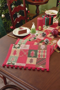 Detail of Christmas table runner with jacquard tree patterns and red pom-poms