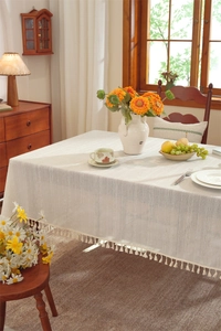 Detail of linen texture tablecloth featuring vertical stripes and white tassel fringe edge