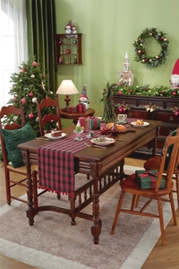 Detail of red and black plaid Christmas table runner with festive pom pom tassels