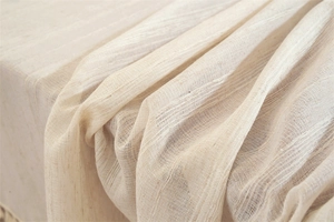 Close-up of light beige faux linen tablecloth featuring delicate fringe and soft texture