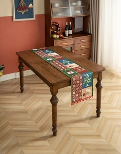 Christmas table runner with santa and tree patterns featuring festive red pompom edges