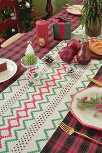 Detail of Christmas crochet table runner with red and green patterns on festive table