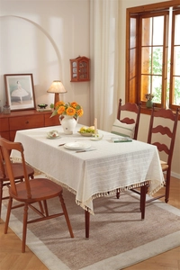 Detailed shot of beige cotton linen tablecloth with raised texture stripes and tassel fringe