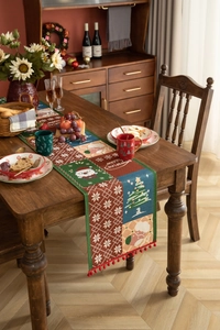 Detailed close-up of woven Christmas table runner with festive jacquard patterns and pom-poms