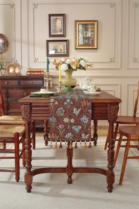Détail d'un chemin de table jacquard floral vintage avec finitions de pompons décoratifs