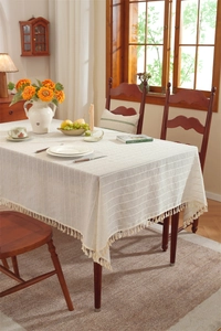 Close-up of beige faux linen tablecloth with horizontal stripe texture and tassel fringe