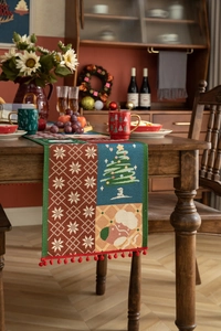 Macro detail of Christmas table runner with festive jacquard patterns and red pom-poms
