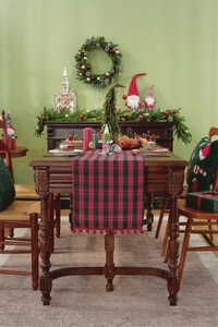 Detail of red and black plaid Christmas table runner with festive red pom pom trim