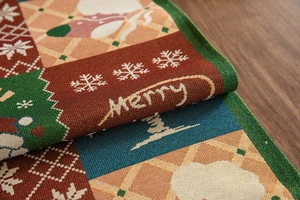 Close-up of woven Christmas table runner featuring Santa Claus and Merry text patterns