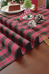 Close-up of red and green plaid Christmas table runner with festive holiday decorations