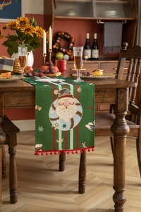 Macro view of Christmas table runner with woven Santa Claus pattern and red pom poms