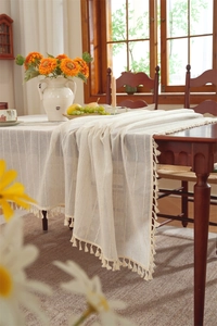 Close-up of linen-style table cloth featuring vertical stripes and elegant fringe tassels