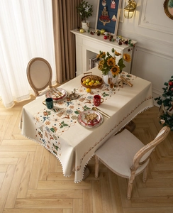 Close-up of Christmas tablecloth showing white pom-pom fringe and reindeer pattern