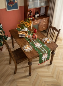 Detailed view of forest green Christmas table runner with Santa motifs and red pompoms
