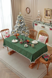 Detailed view of green Christmas tablecloth with gold snowflakes and white pom-pom trim