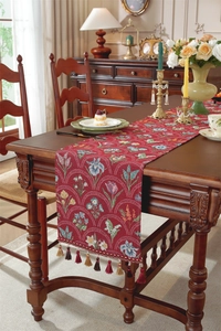 Détail d'un chemin de table jacquard rouge foncé avec motifs floraux et pompons
