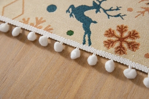 Close-up of Christmas tablecloth with elk patterns and soft white pom-pom trim
