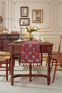 Gros plan détaillé d'un chemin de table en jacquard rouge foncé avec franges à glands