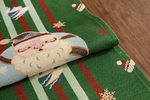 Detail of green Christmas table runner with woven Santa Claus and snowflake patterns