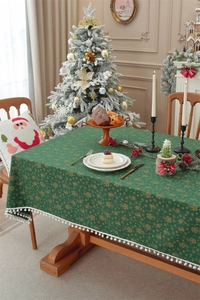 Detail of green Christmas tablecloth with gold bell prints and white pom-pom fringe