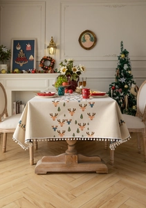 Close-up of Christmas reindeer jacquard tablecloth with white pom-pom fringe edges