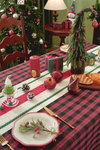 Detailed close-up of Christmas plaid tablecloth and woven runner with festive table setting