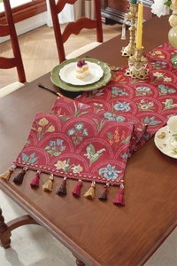 Gros plan d'un chemin de table rouge à fleurs avec des franges sur une table en bois massif