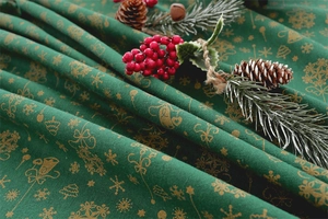 Detailed view of green Christmas tablecloth with gold bell and snowflake foil prints
