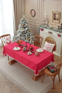 Close-up of red Christmas tablecloth with gold snowflake patterns and white pom-pom fringe