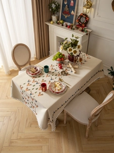 Detailed view of Nordic Christmas tablecloth with reindeer prints and white pompom fringes
