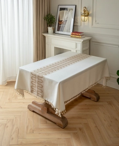 Close-up of geometric jacquard patterns and elegant tassel fringe on a cream tablecloth