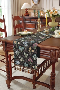 Détail d'un chemin de table jacquard floral vintage avec glands sur table en bois
